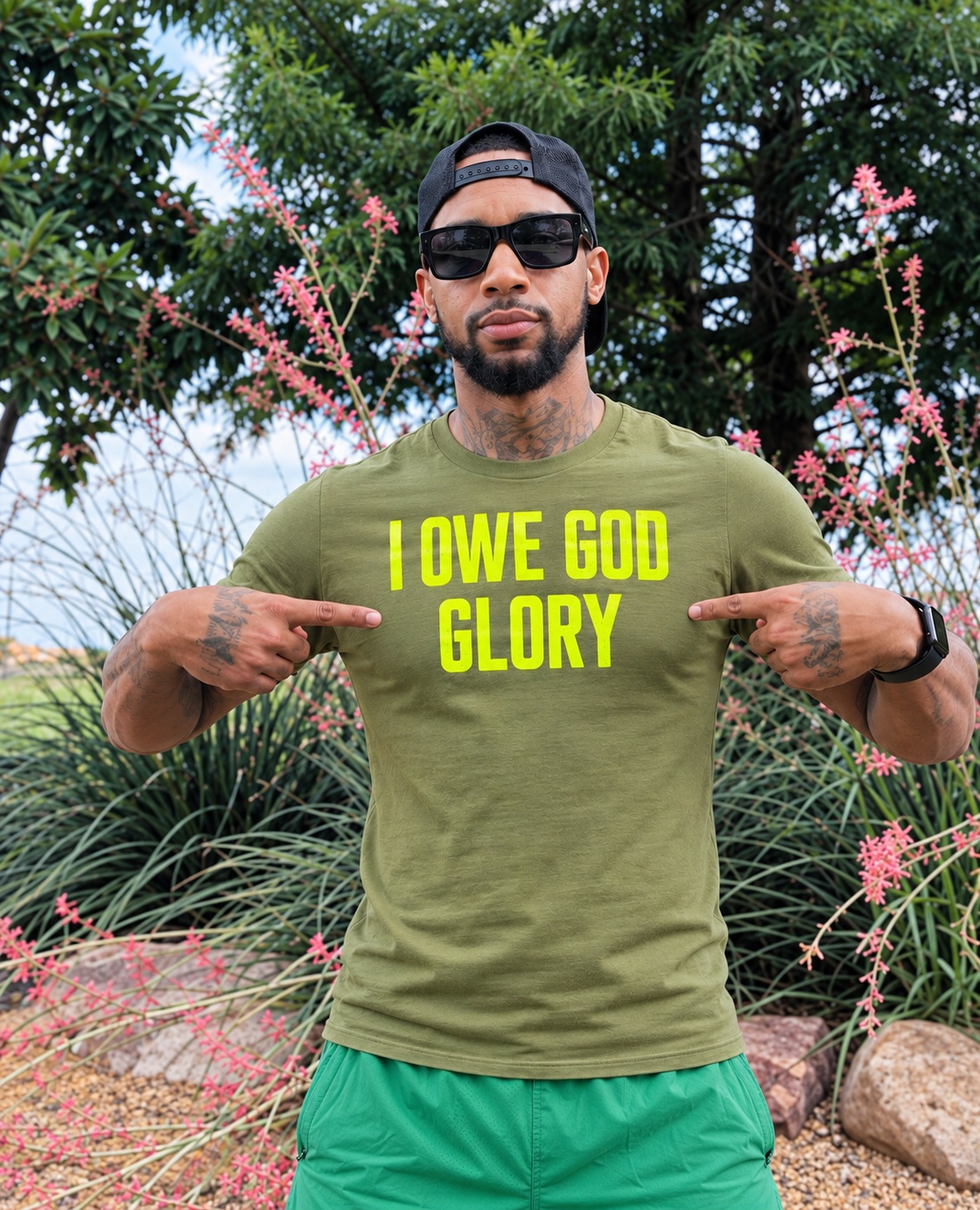 Waist-up outdoor portrait of Torrian wearing an olive I Owe God Glory shirt